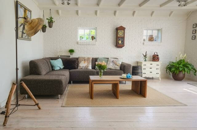 Underground living room with small windows, grey sectional sofa, brown wooden table